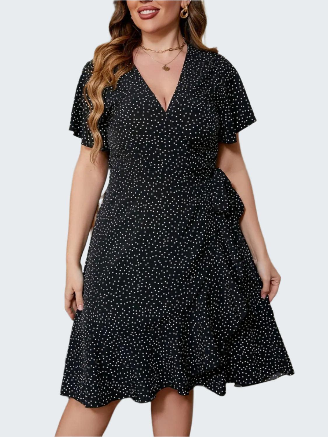 A woman wearing a plus size polka dot flutter sleeve mini dress in black with white dots.