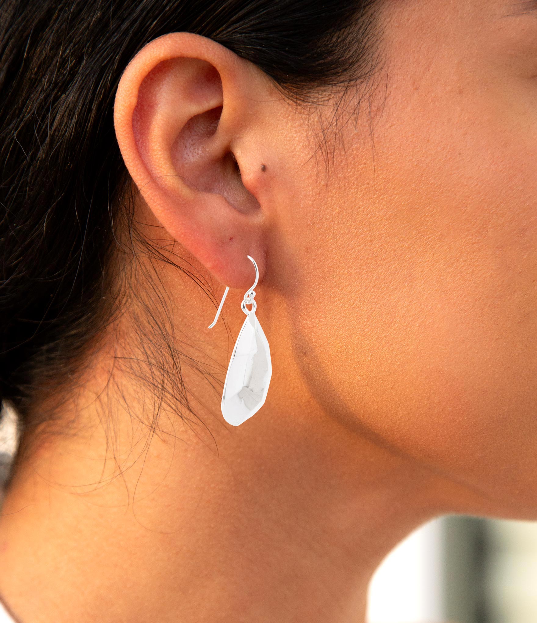 Close-up of a person wearing a teardrop-shaped earring.