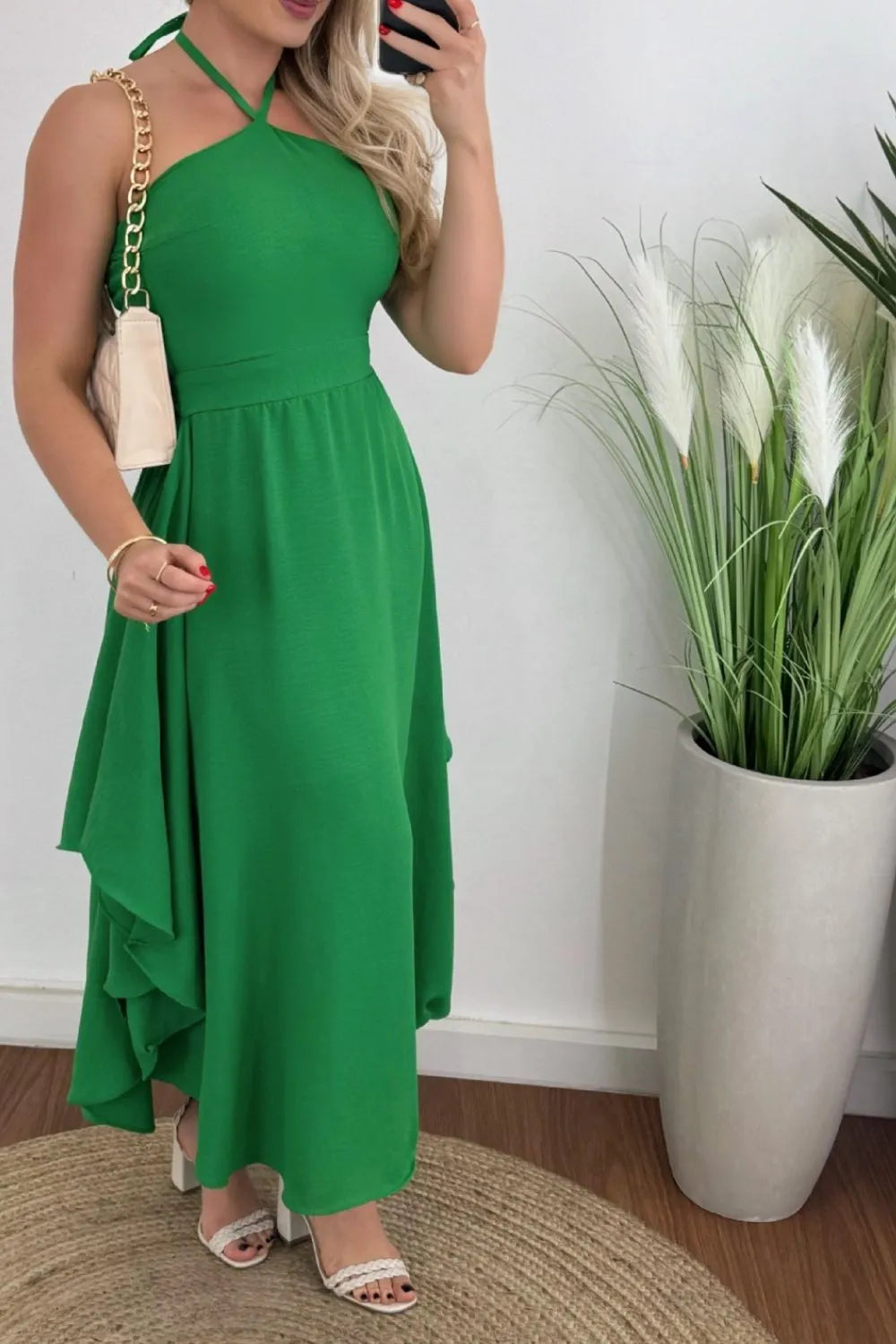 A model wearing a black halter neck dress with a printed floral pattern, paired with white accessories.