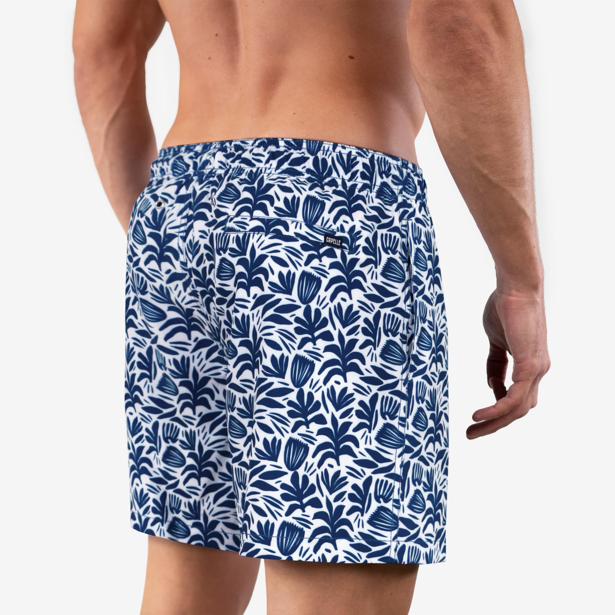 Person wearing blue and white patterned swim shorts on a plain background
