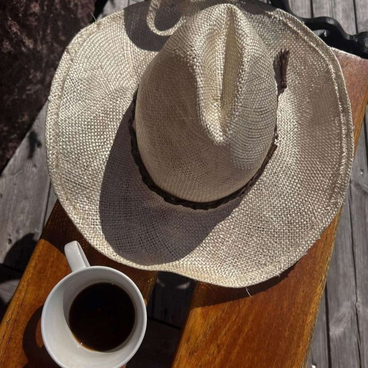 Straw hat and cup of coffee on a wooden surface