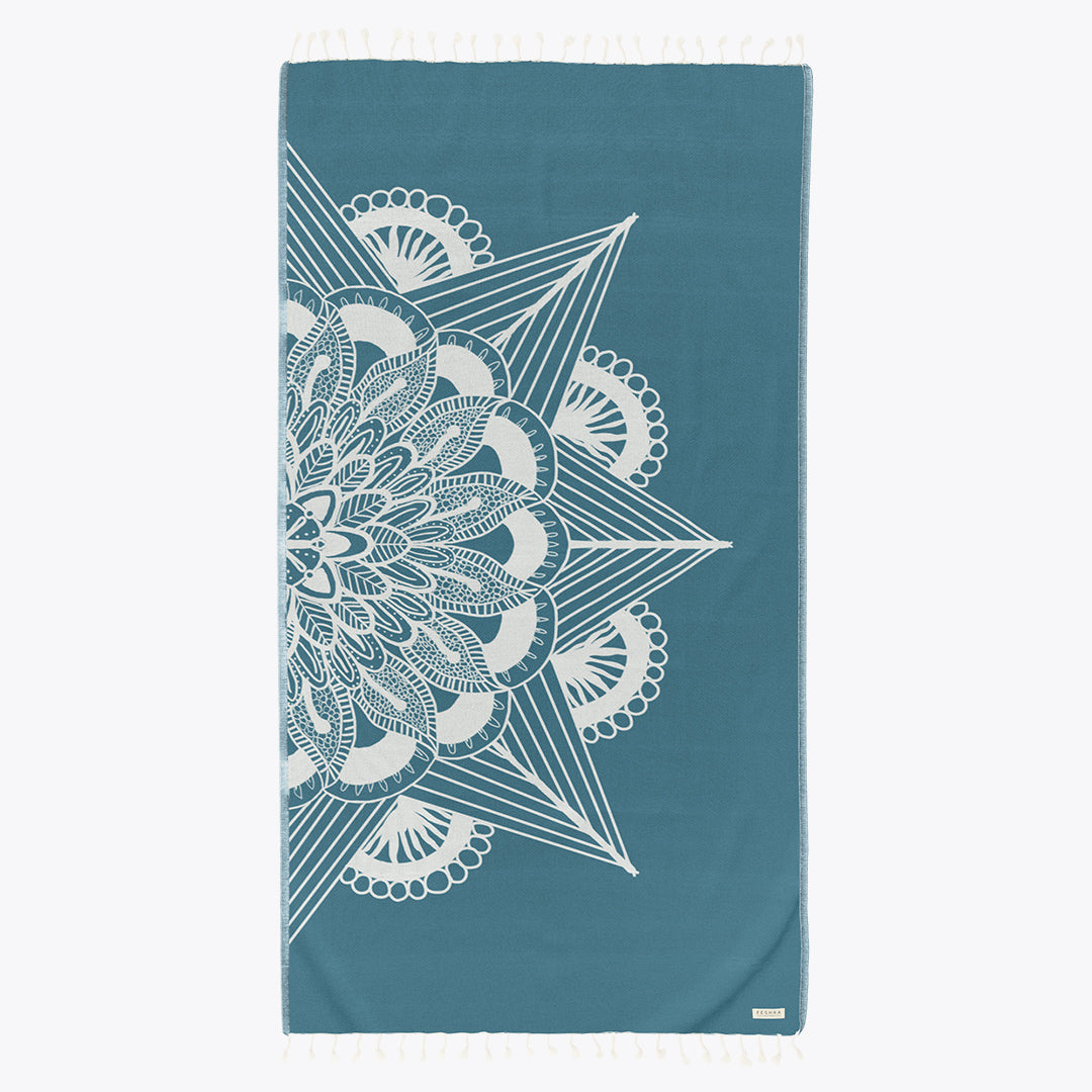 Teal towel with white geometric pattern on a white background