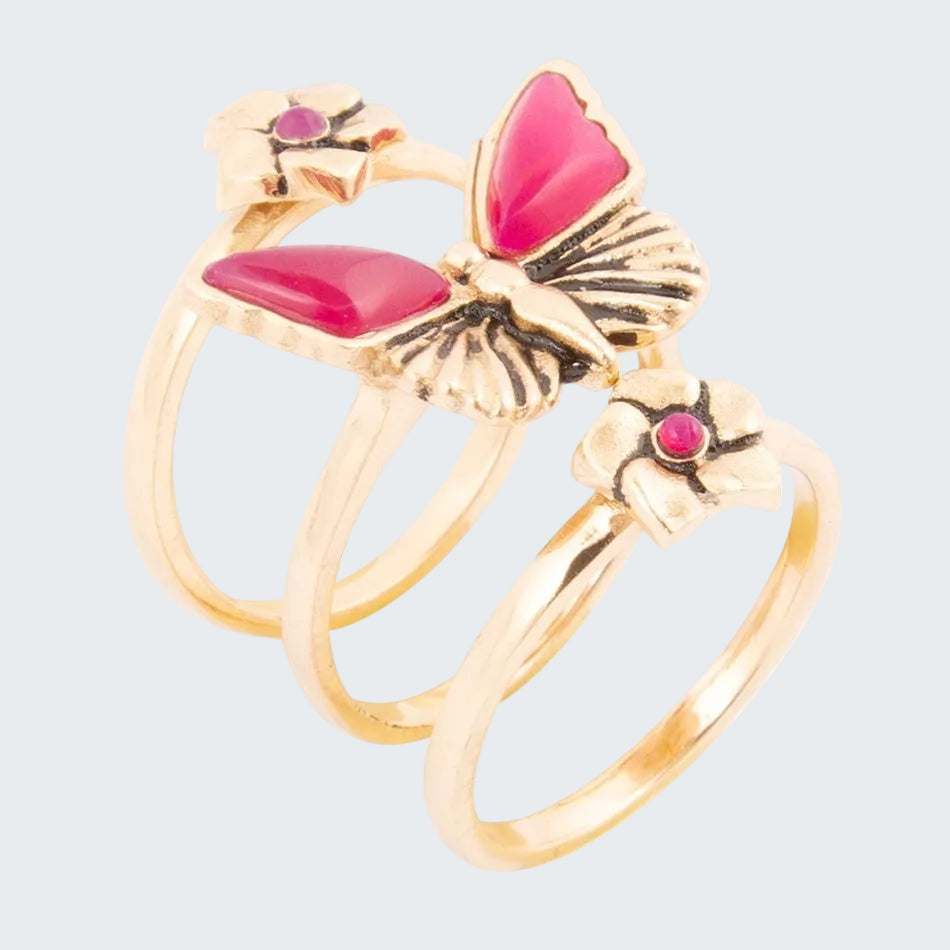 Gold butterfly ring with pink gemstones on a white background
