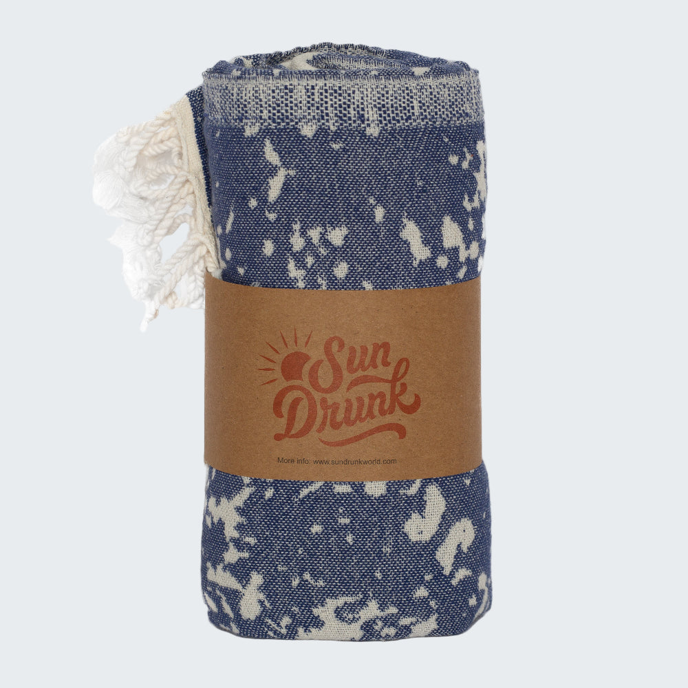 Blue and white patterned blanket with 'Sun Drunk' branding on a white background