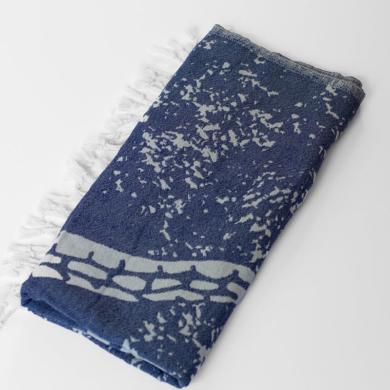 Folded blue and white patterned towel on a light gray background