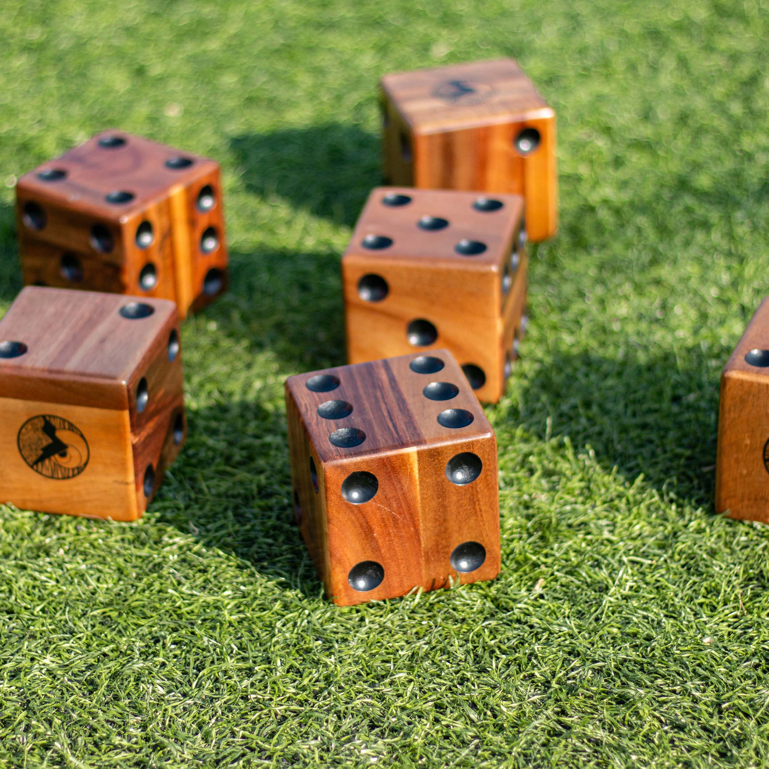 Wooden dice with black dots on a grassy surface