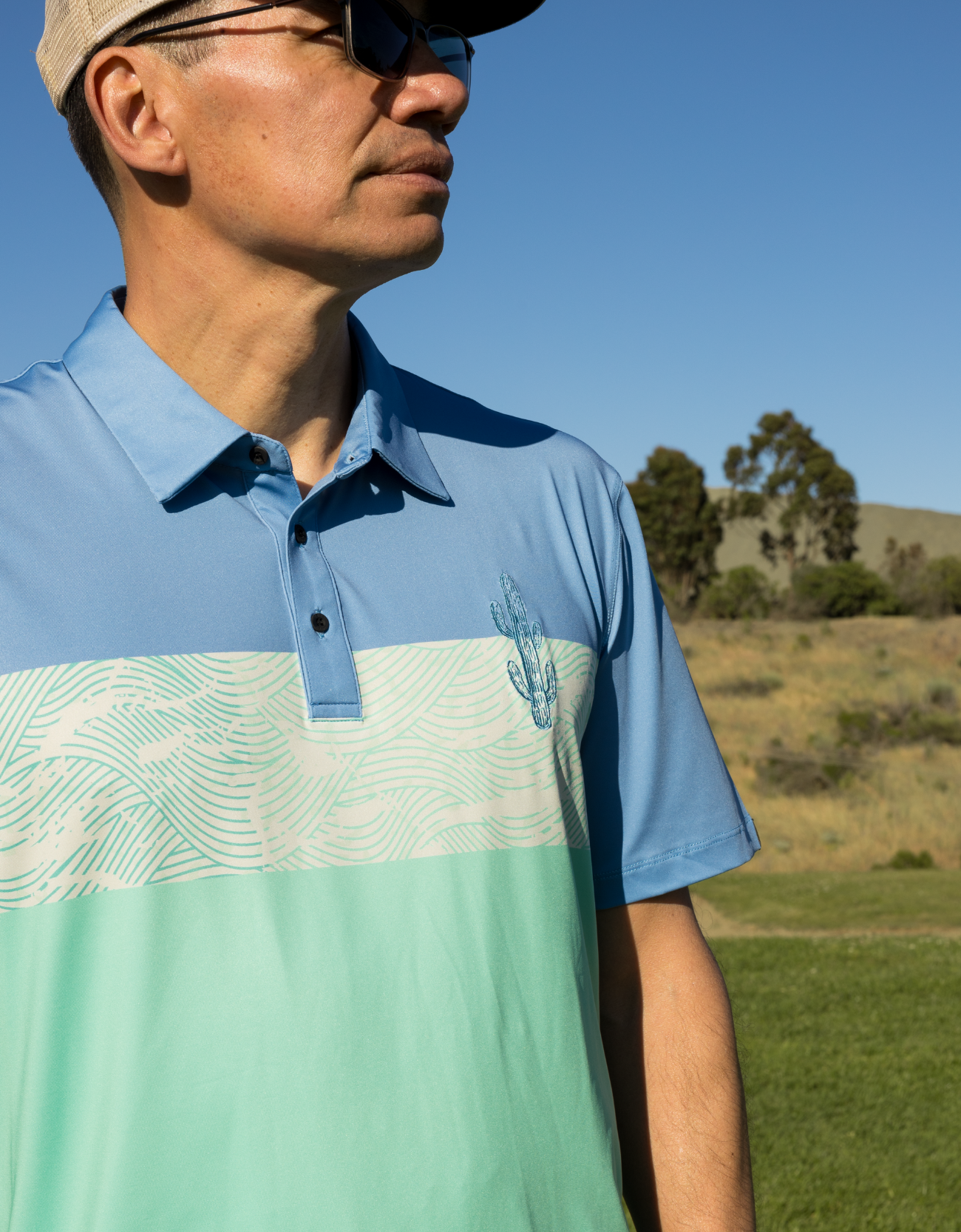Man wearing a blue and green patterned polo shirt outdoors.