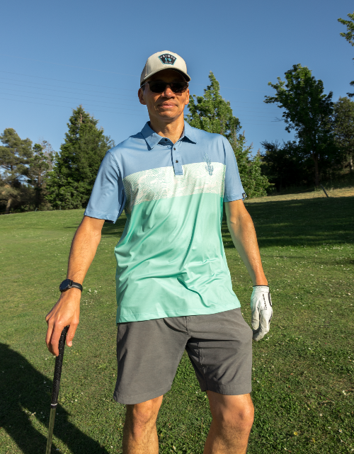 Man in golf attire on a golf course with trees in the background