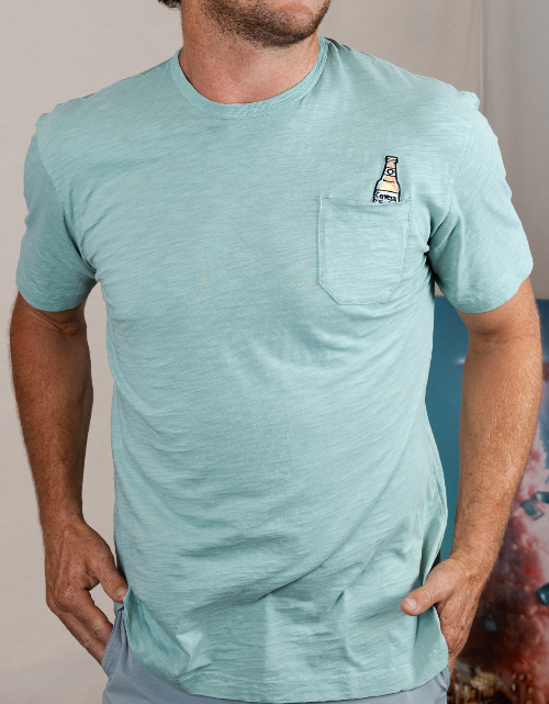 Man wearing a light blue t-shirt with a small graphic on the chest against a neutral background