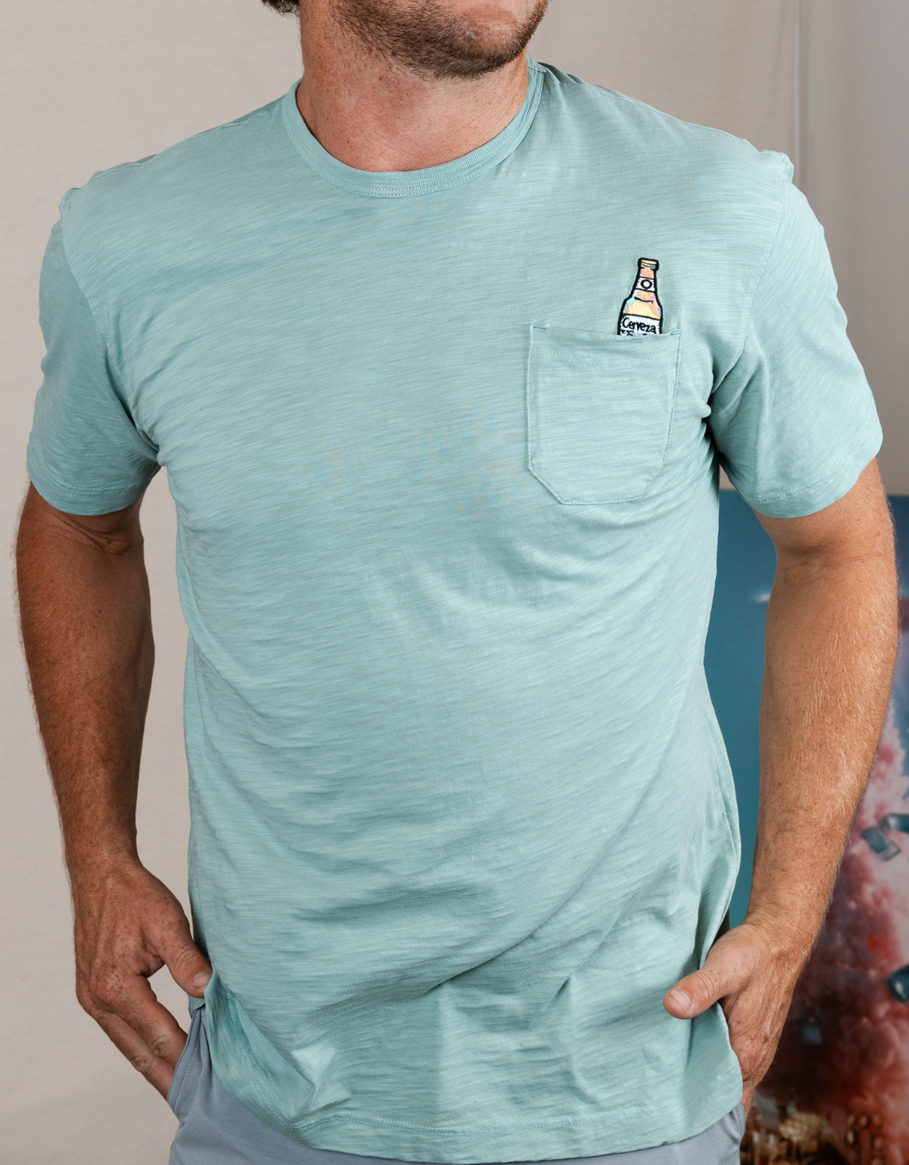 Man wearing a light blue t-shirt with a small graphic on the chest against a neutral background