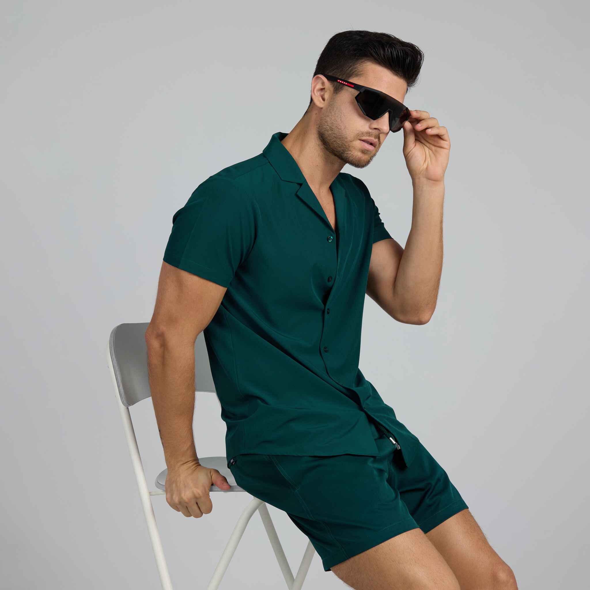 Man wearing a green outfit with sunglasses against a plain background