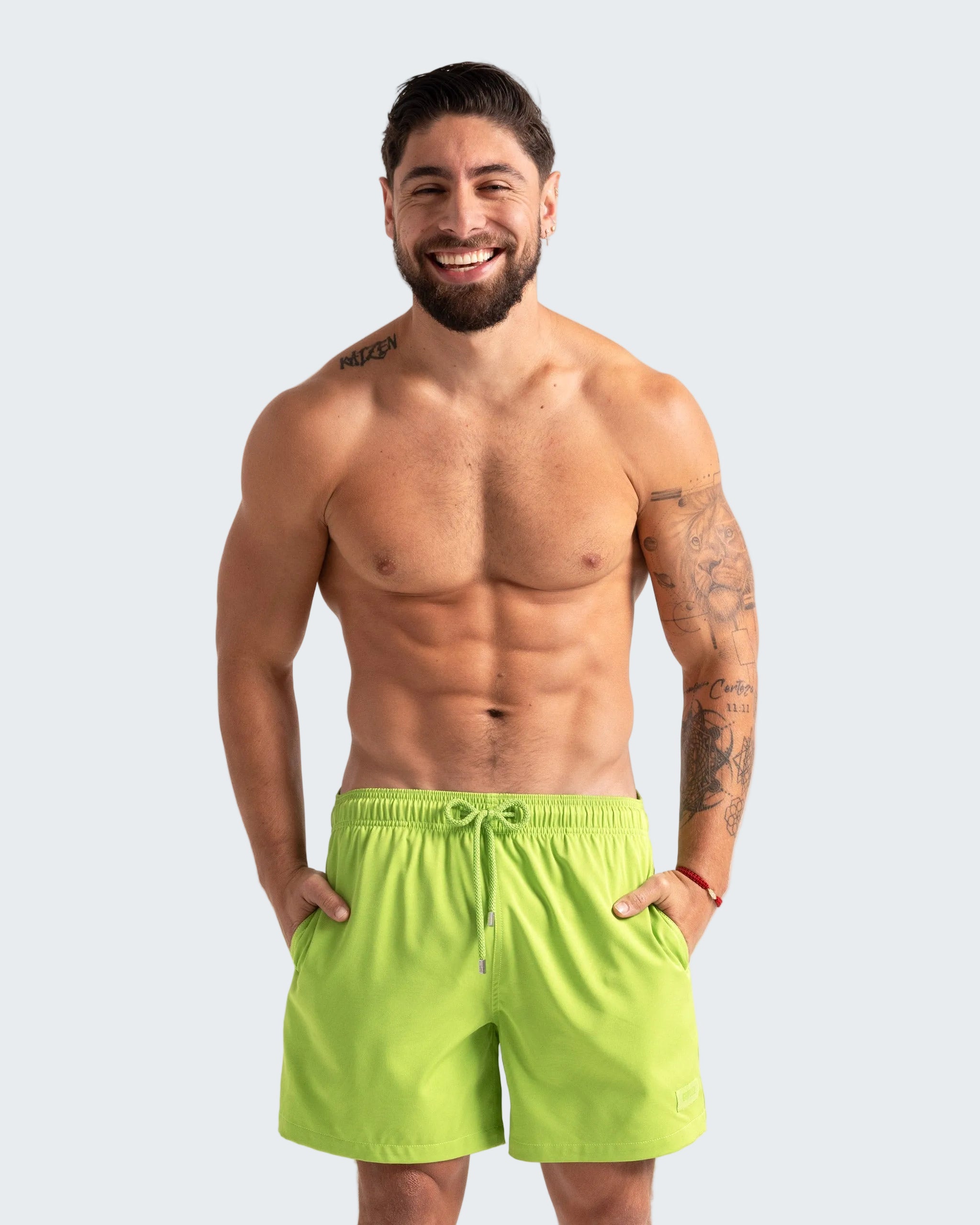 Man wearing bright green shorts on a plain background
