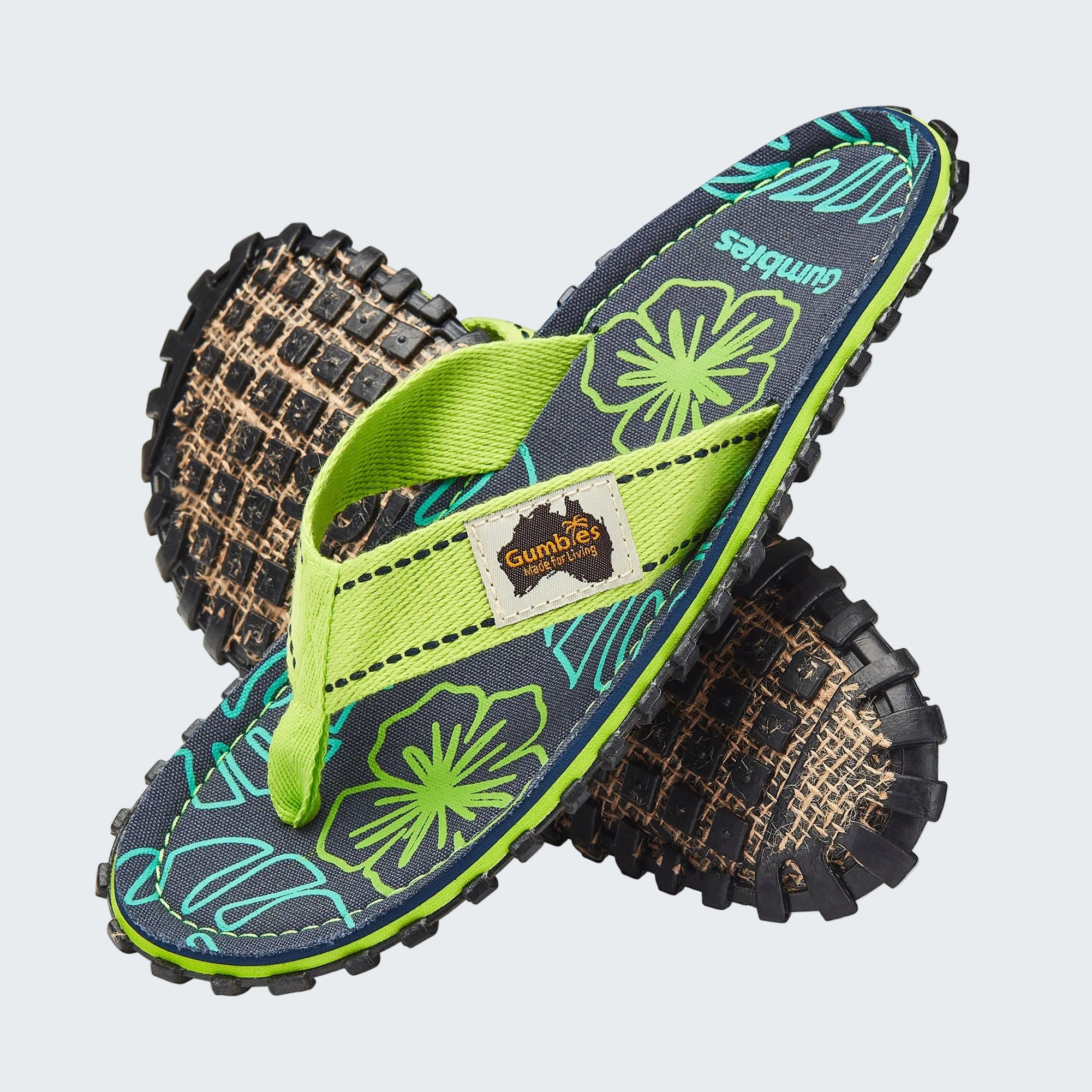 Pair of Gumbies sandals with floral pattern and green strap on a white background