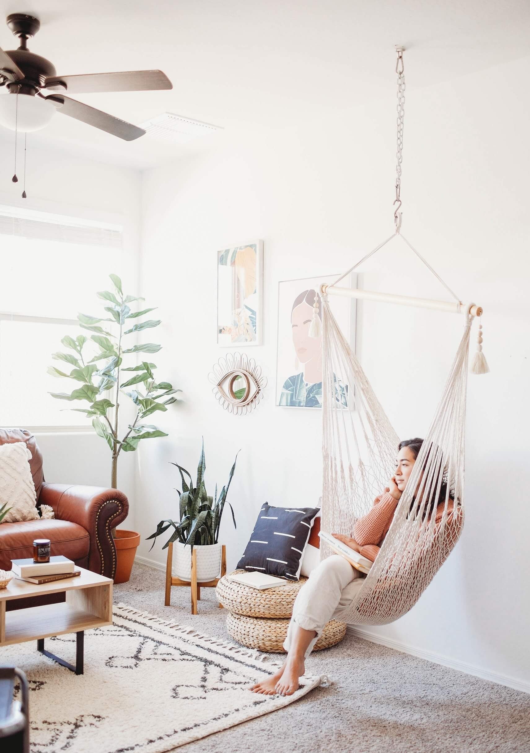 Person relaxing in a hanging chair in a cozy living room.