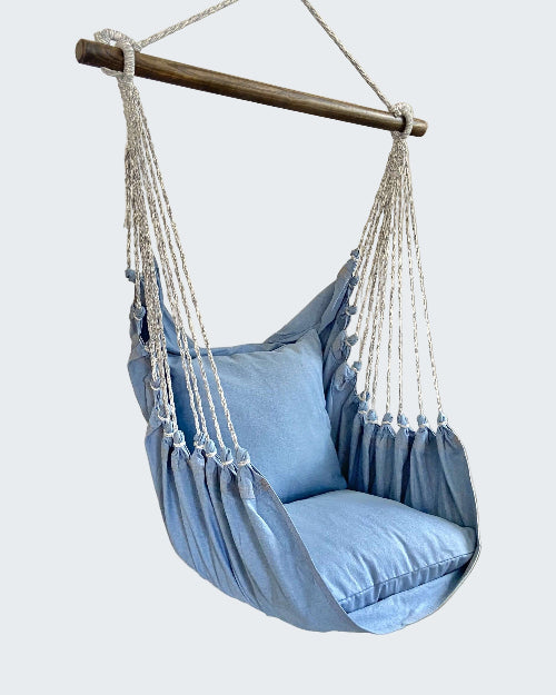 Blue hammock chair with white ropes in a room with a plant and candle.