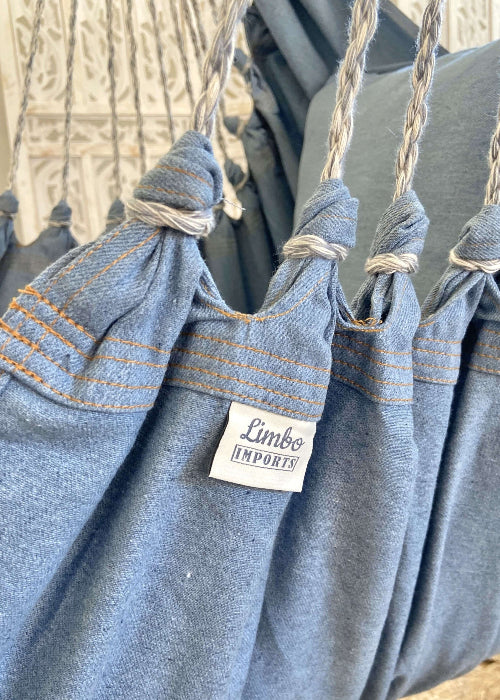 Blue hammock with 'Lumbo Imports' label against a blurred natural background