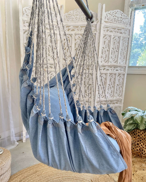Blue hammock chair hanging from a decorative white archway.