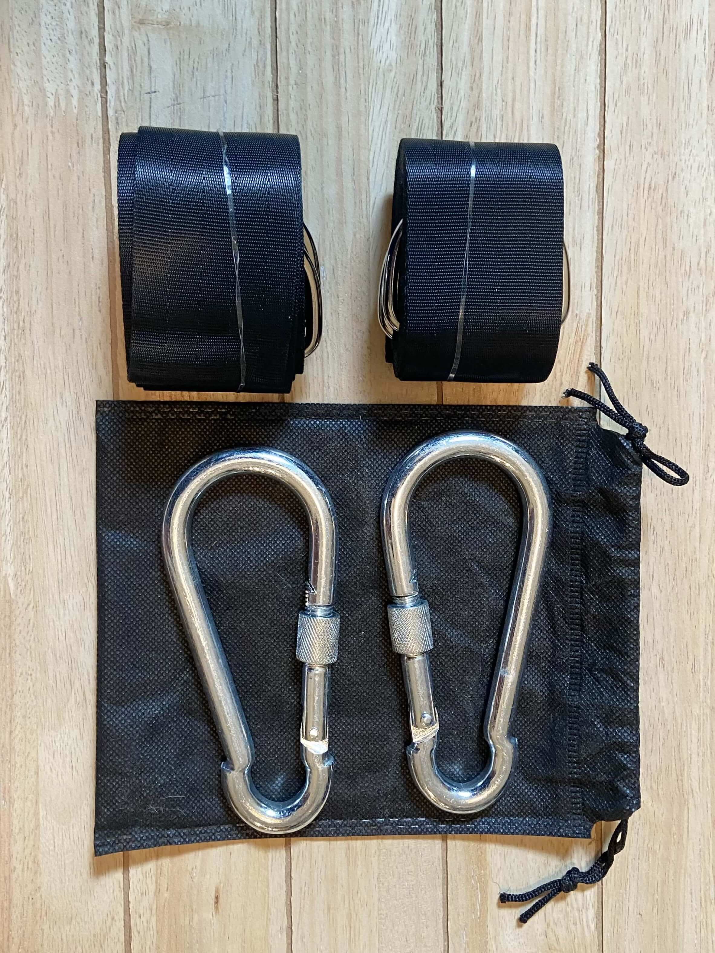 Two metal carabiners with black straps on a wooden surface