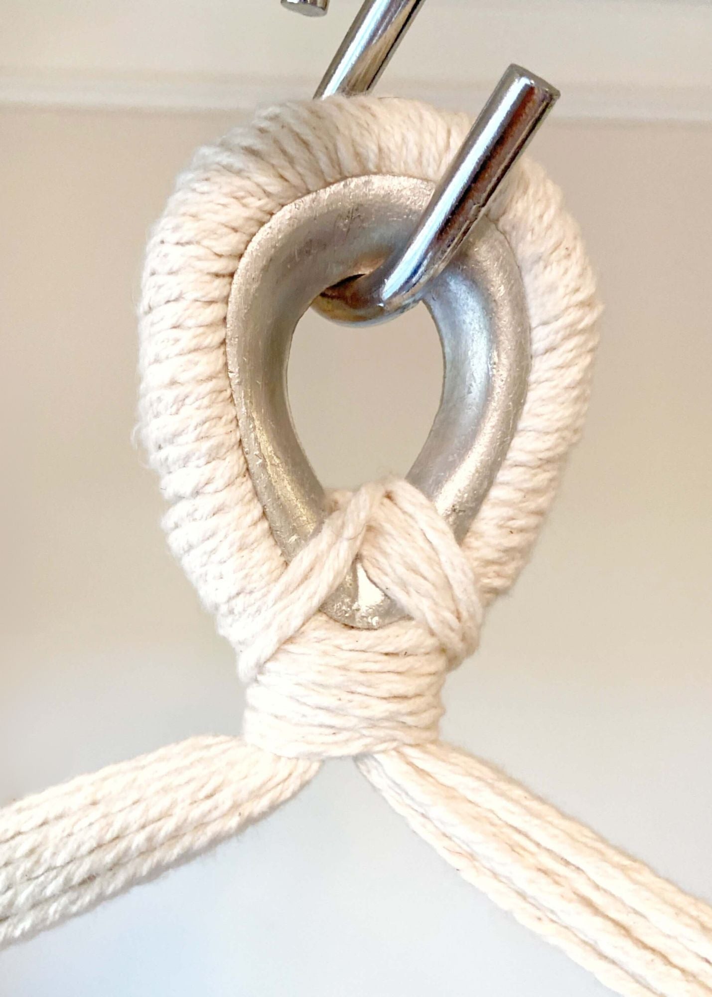 Close-up of a white rope tied in a knot with a metal hook on a white background