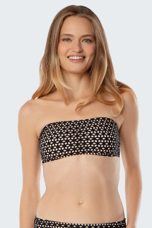 Woman wearing a black and white polka dot strapless top on a plain background