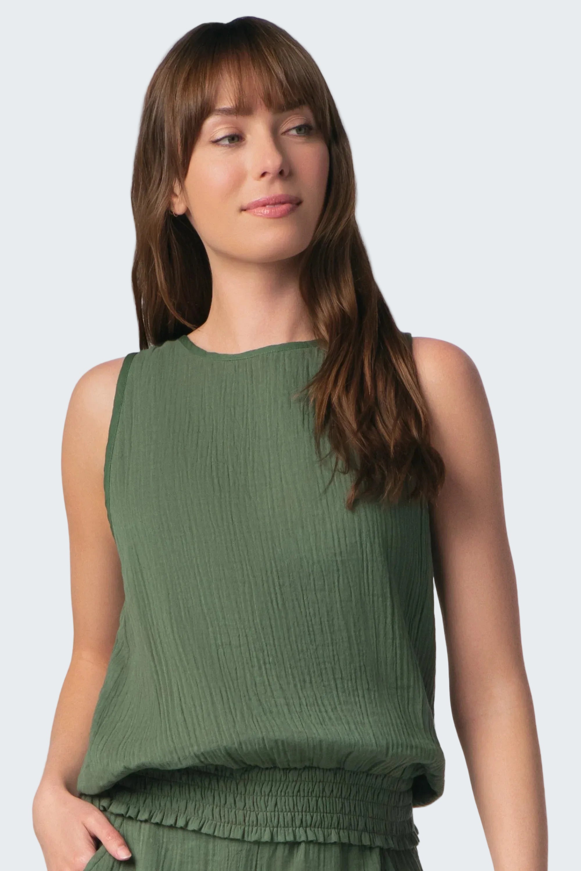 Woman wearing a green sleeveless top against a white background