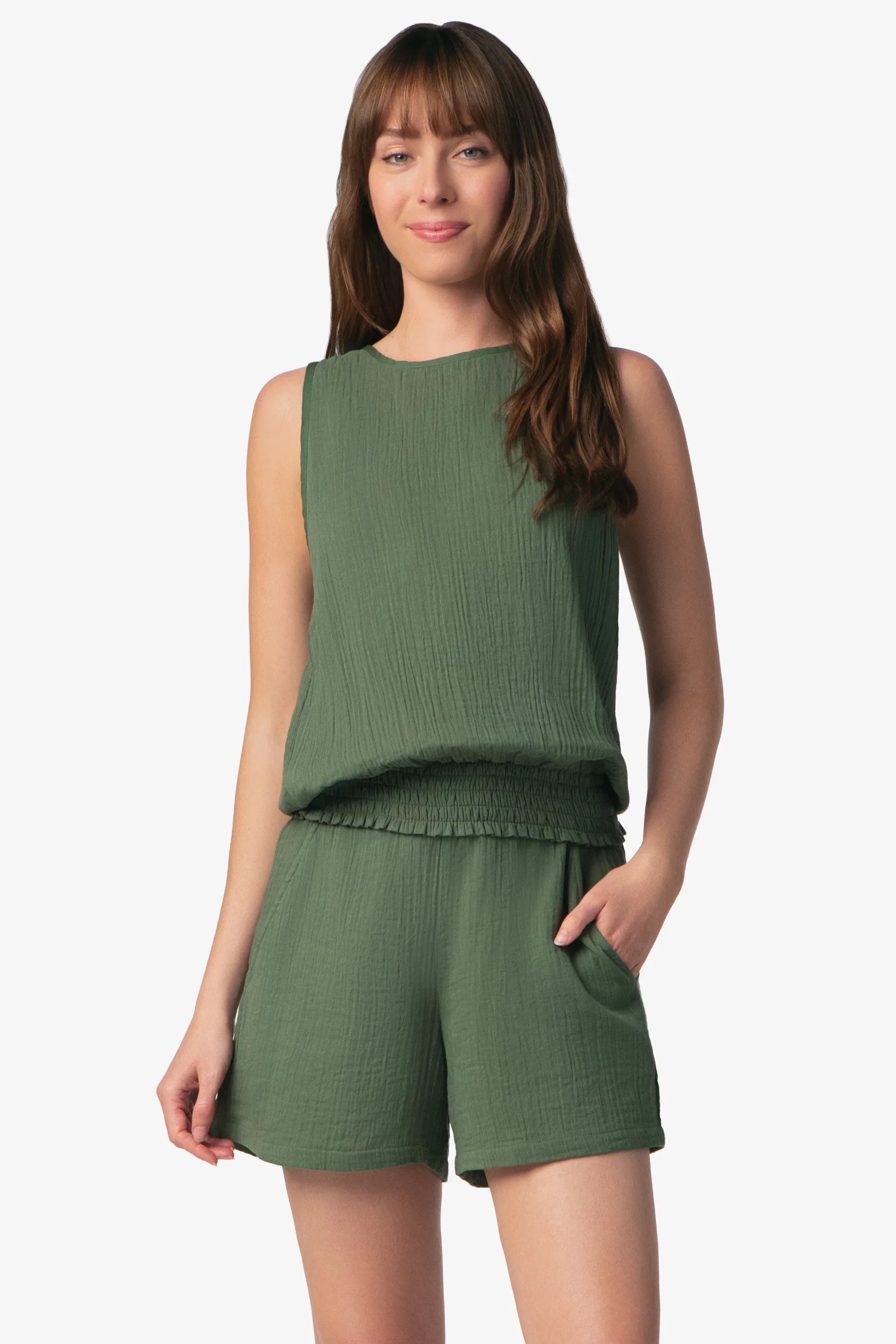 Woman wearing a green sleeveless top and shorts on a white background