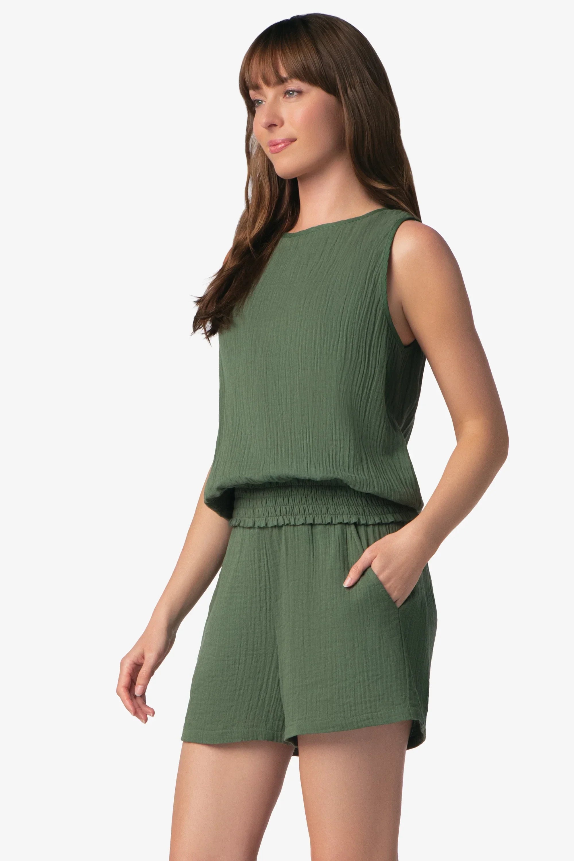 Woman wearing a green sleeveless top and shorts set on a white background