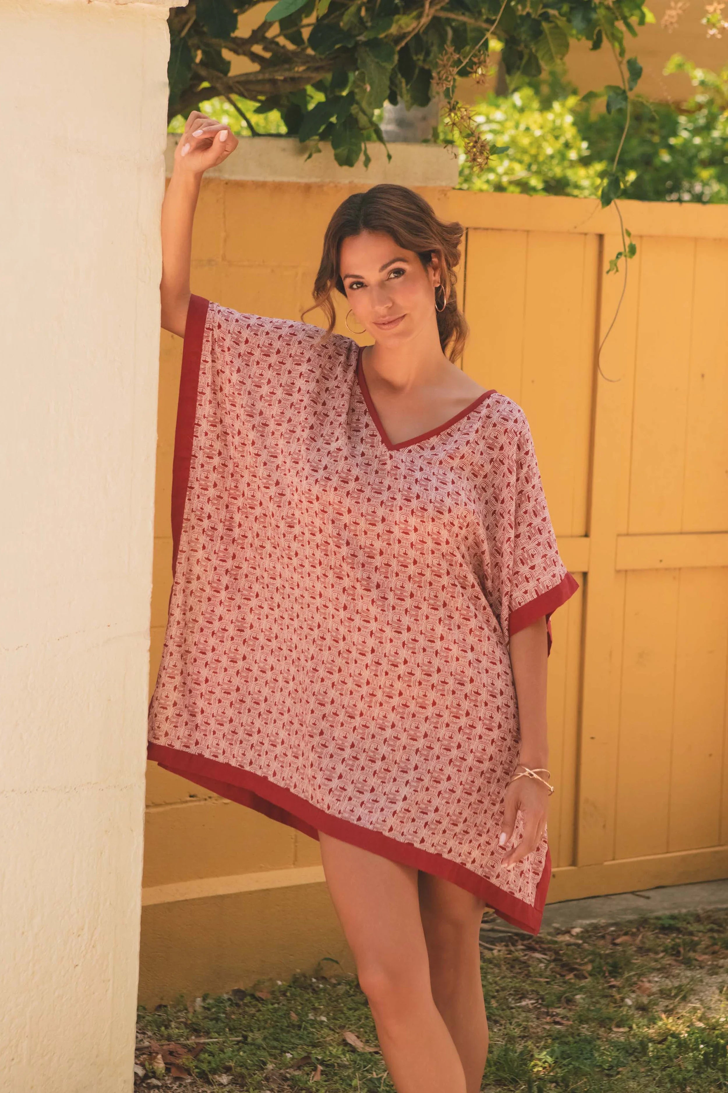 Woman wearing a red and white patterned dress standing outdoors.