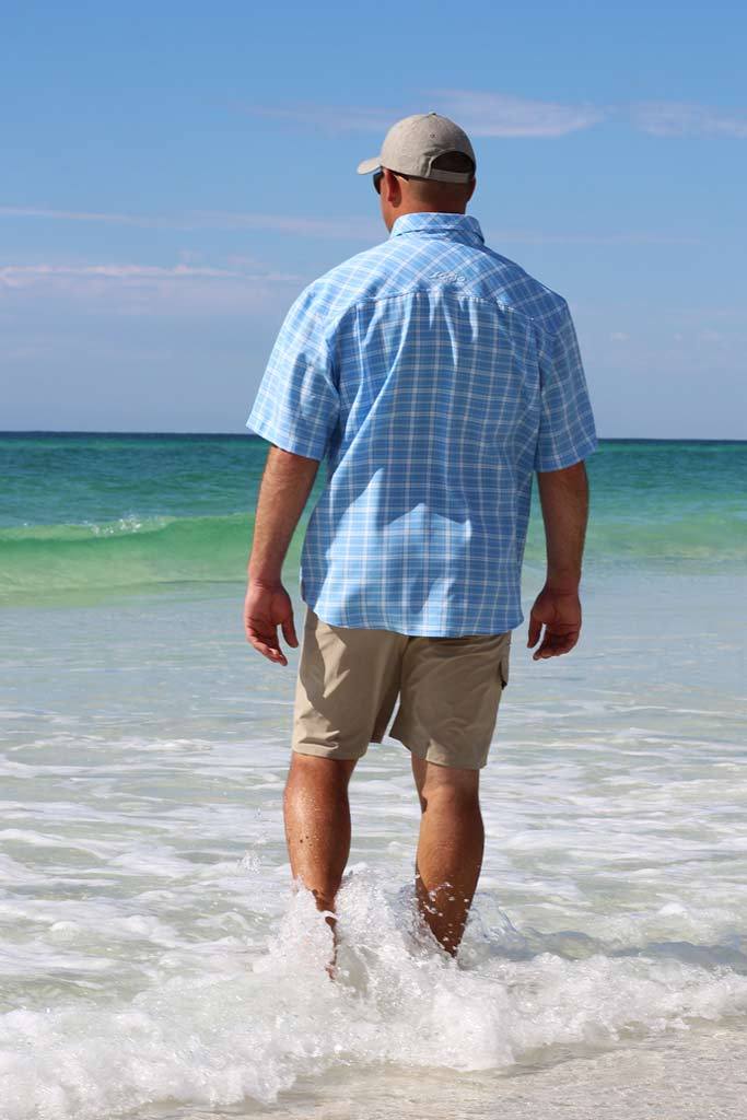Man walking on a beach with blue ocean and clear sky