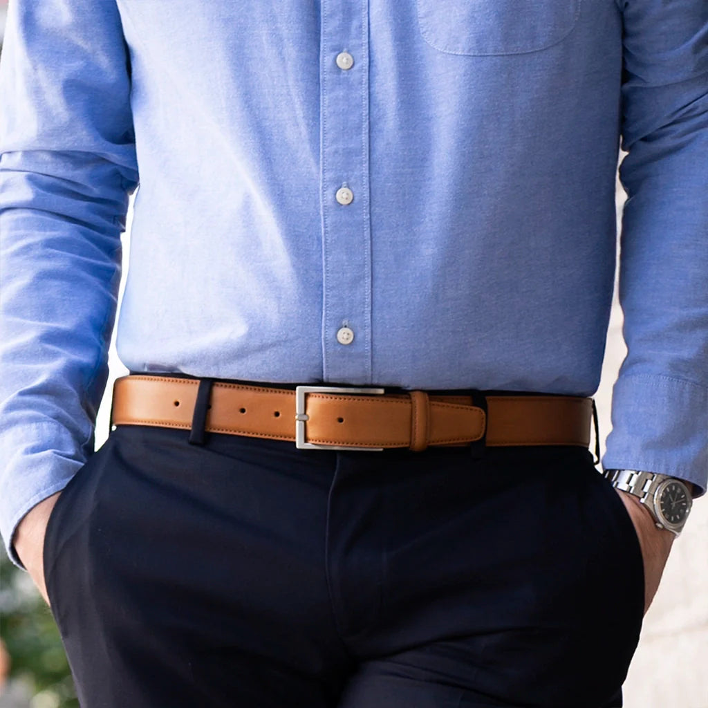 Person wearing a blue shirt, dark pants, and a brown belt with a watch.