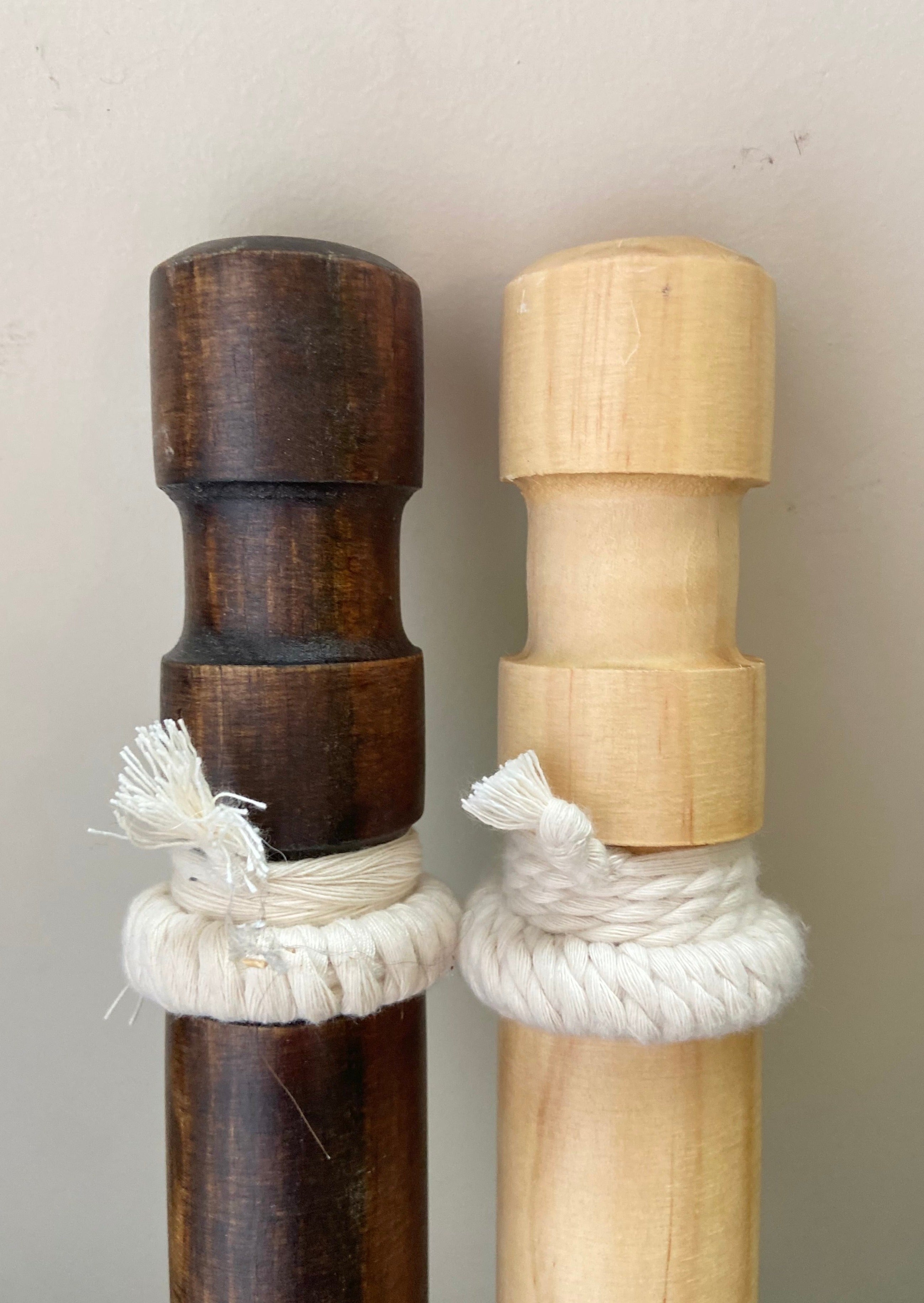 Two wooden sticks with rope wrapping on a plain background
