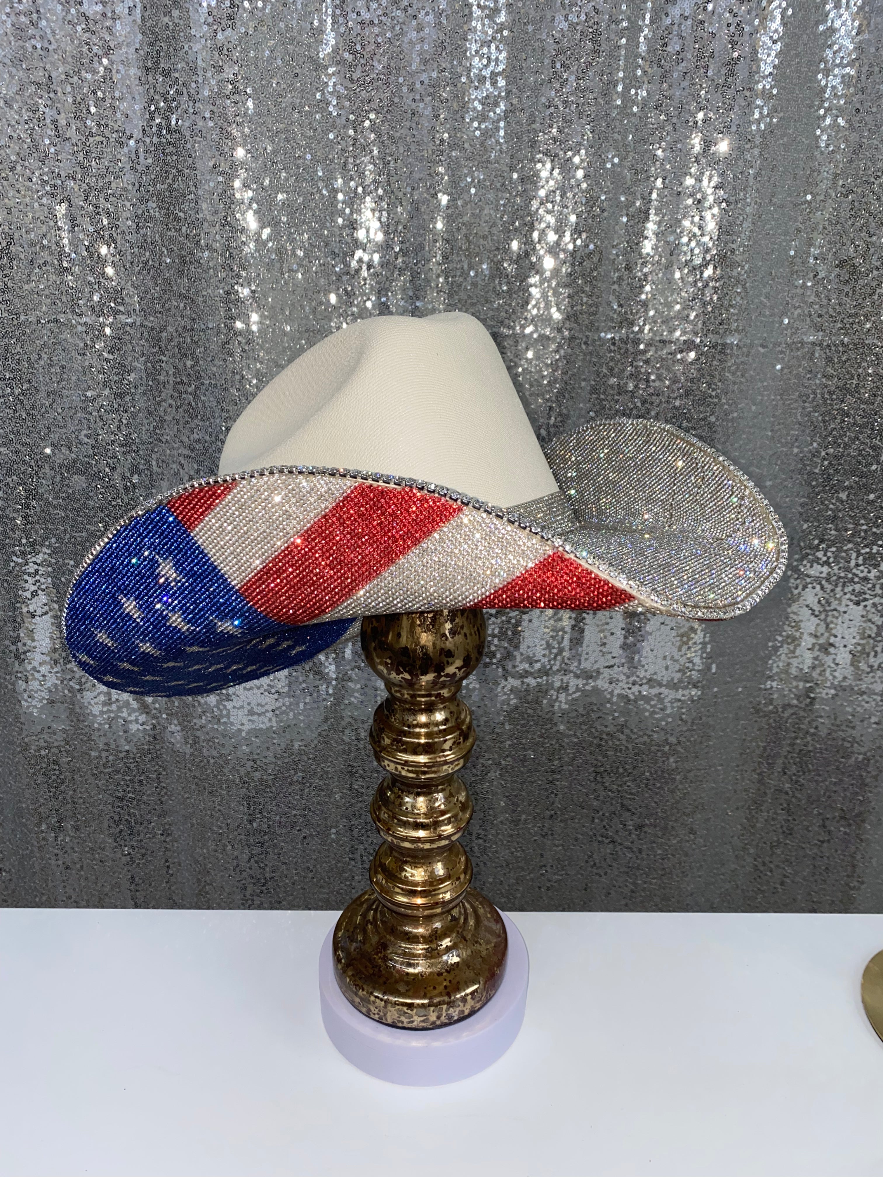 Decorative lamp with a beaded American flag design on a metallic stand against a textured gray background.