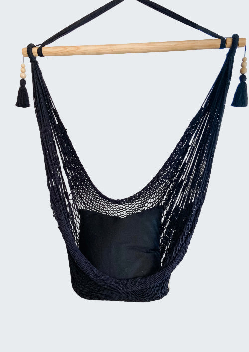 Navy blue hammock chair with a pillow in a room with decorative elements.