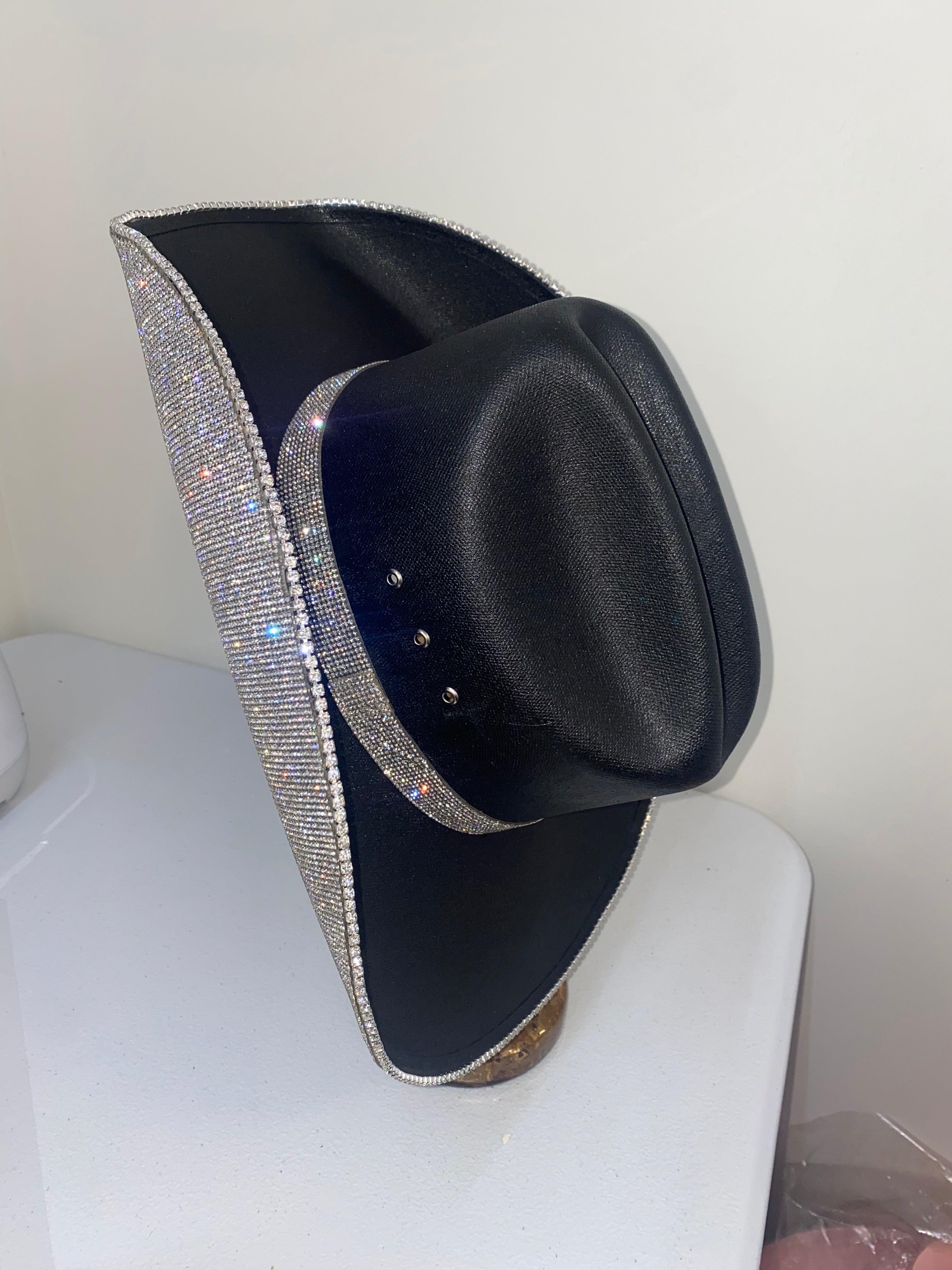 Black cowboy hat with a rhinestone band on a white surface