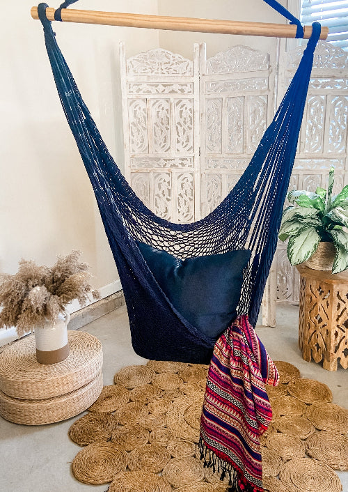 Navy blue hammock chair with a colorful blanket in a room with decorative elements.