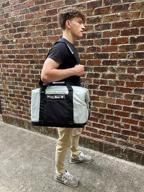 Person holding a Polar Bear insulated bag against a brick wall