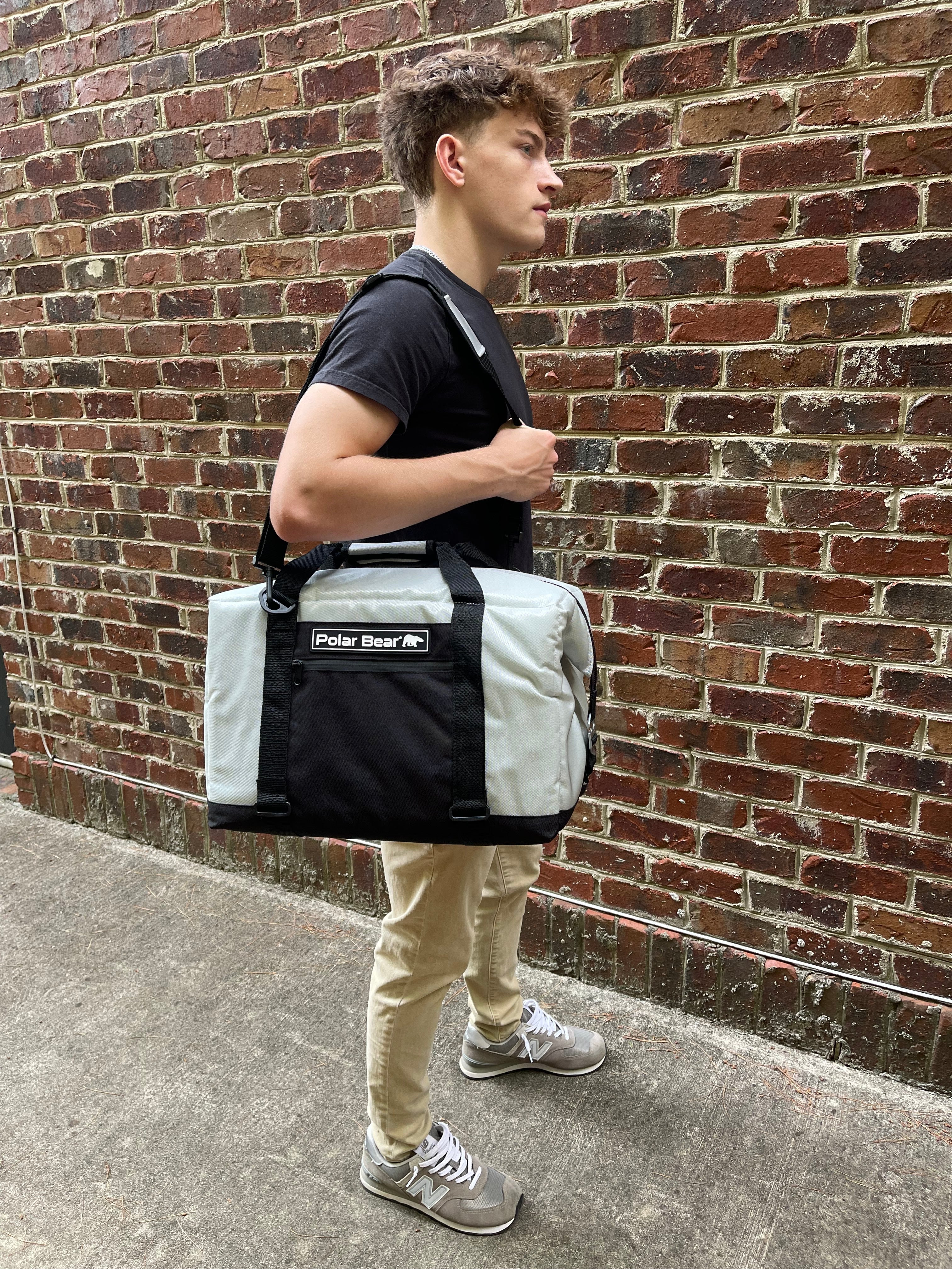 Person holding a Polar Bear insulated bag against a brick wall