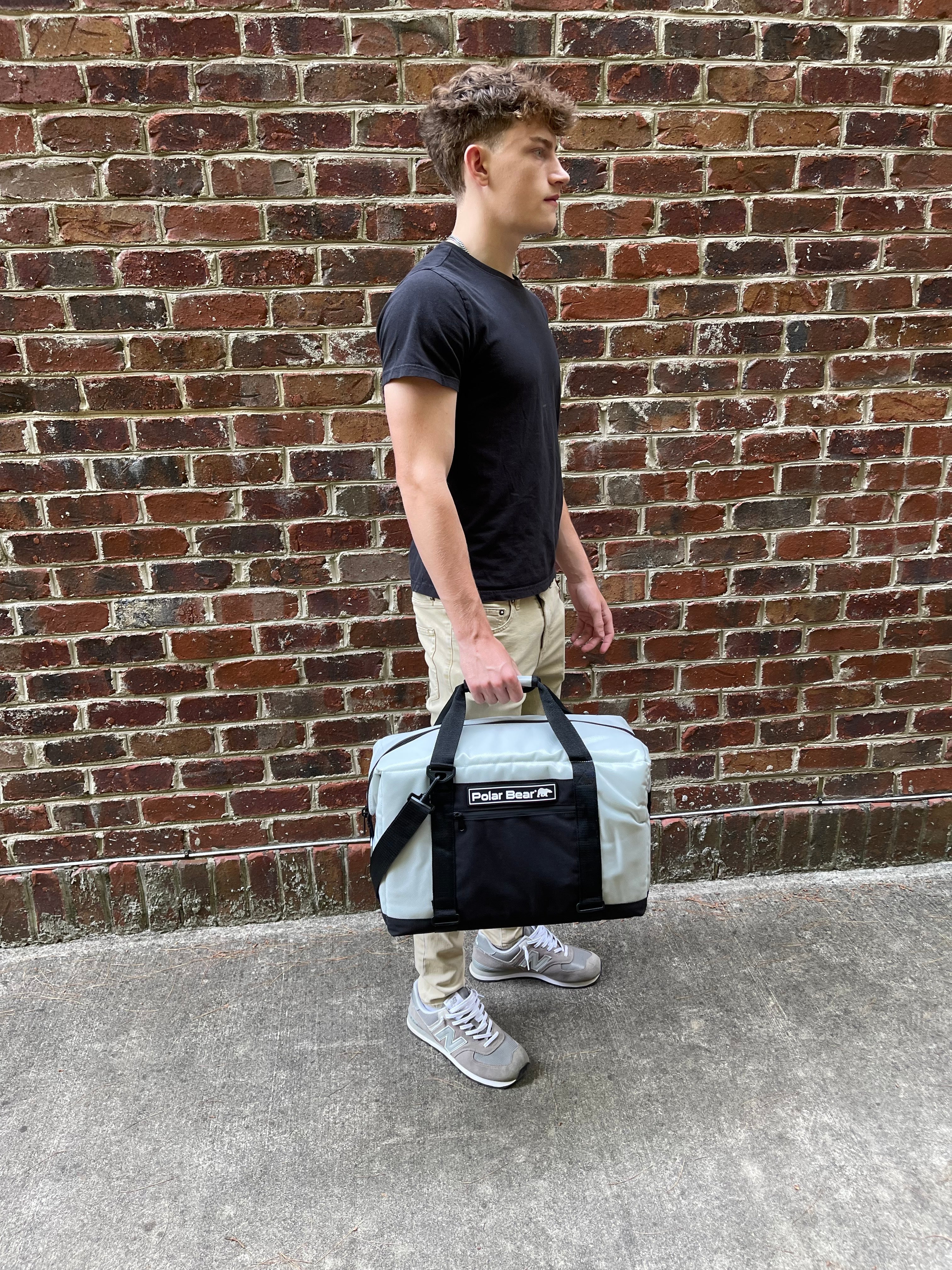 Person holding a cooler bag against a brick wall