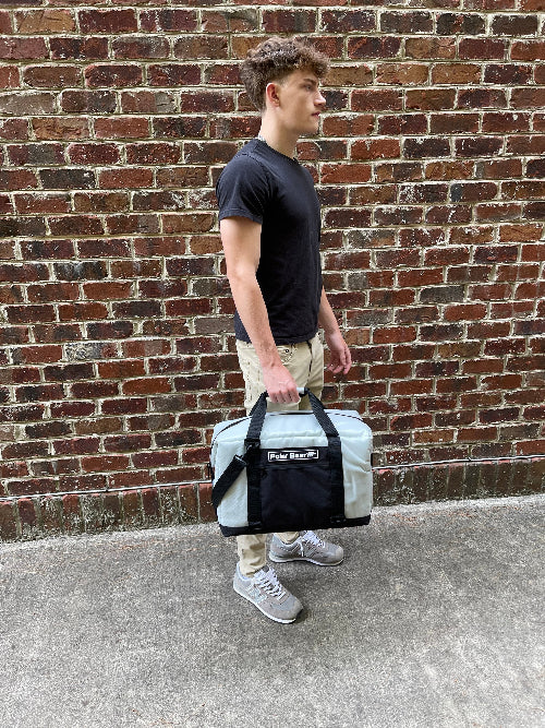 Person holding a cooler bag against a brick wall