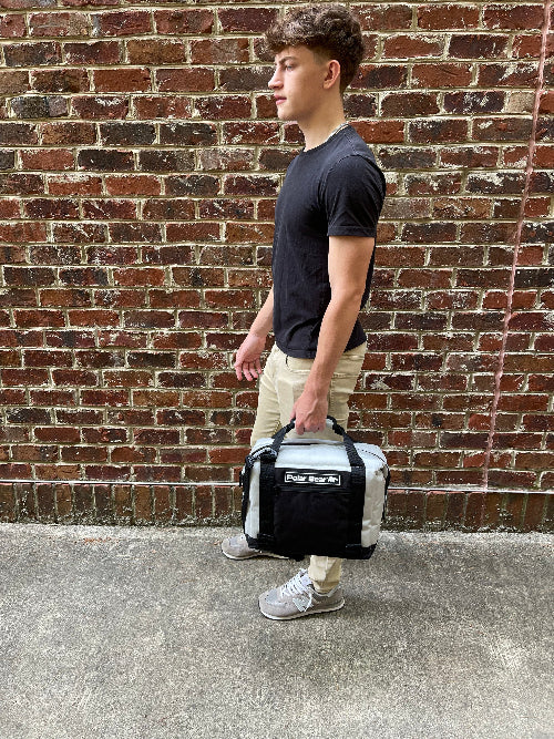 Person holding a cooler bag against a brick wall