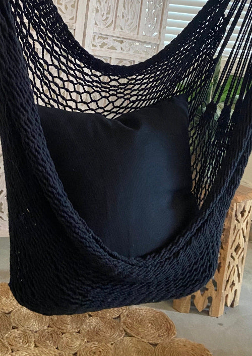 Black hammock chair with a pillow in a decorative setting