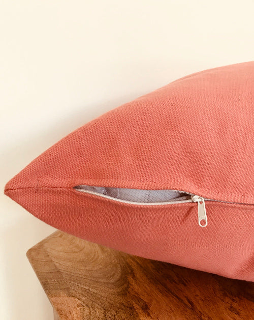 Pink pillow with a zipper on a wooden surface