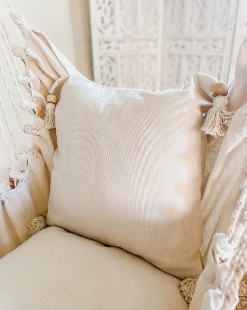 Beige pillow with tassels on a textured chair