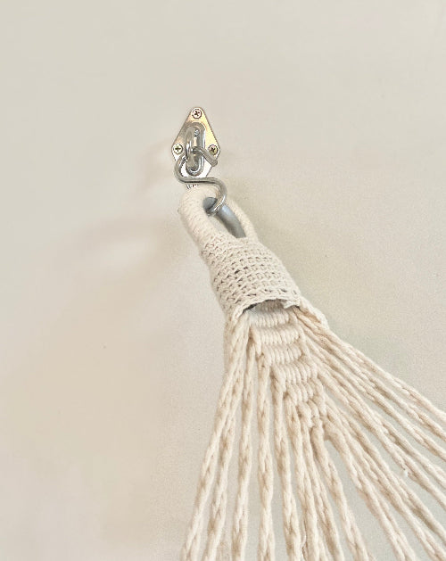 Close-up of a beige tassel with a metal clip on a beige background