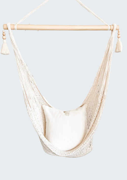 White hammock chair with a pillow in a room with decorative elements.