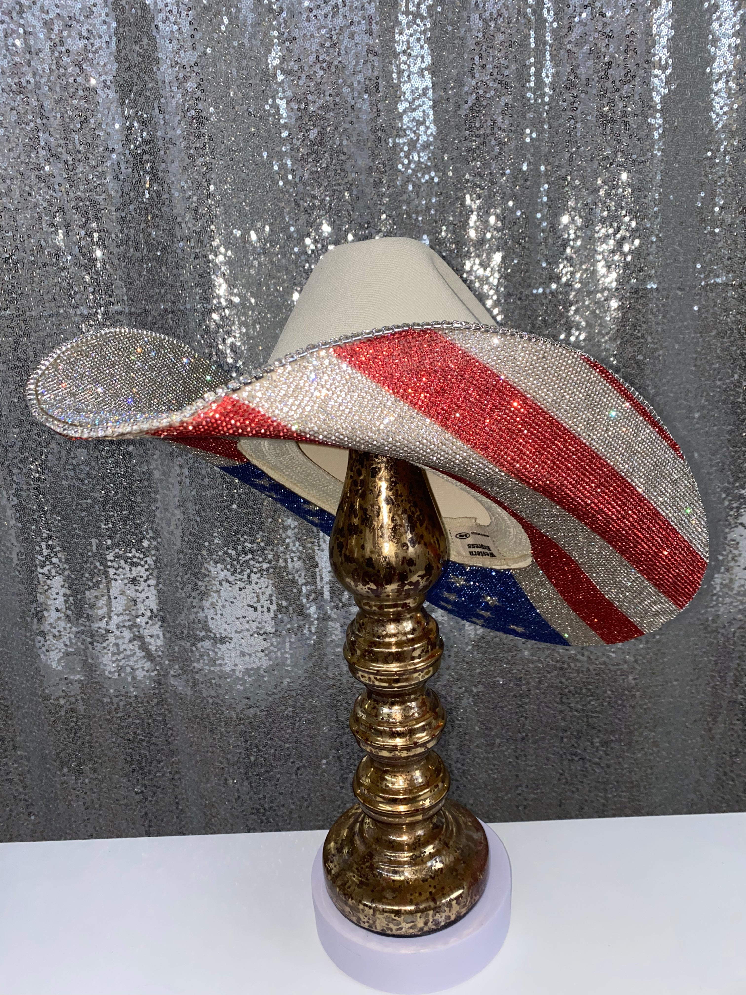 Decorative hat with American flag design on a gold stand against a textured gray background