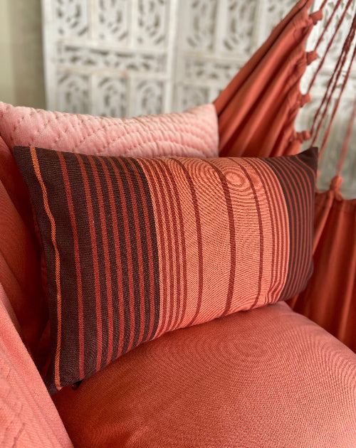 Striped pillow on a textured surface with a decorative wall in the background