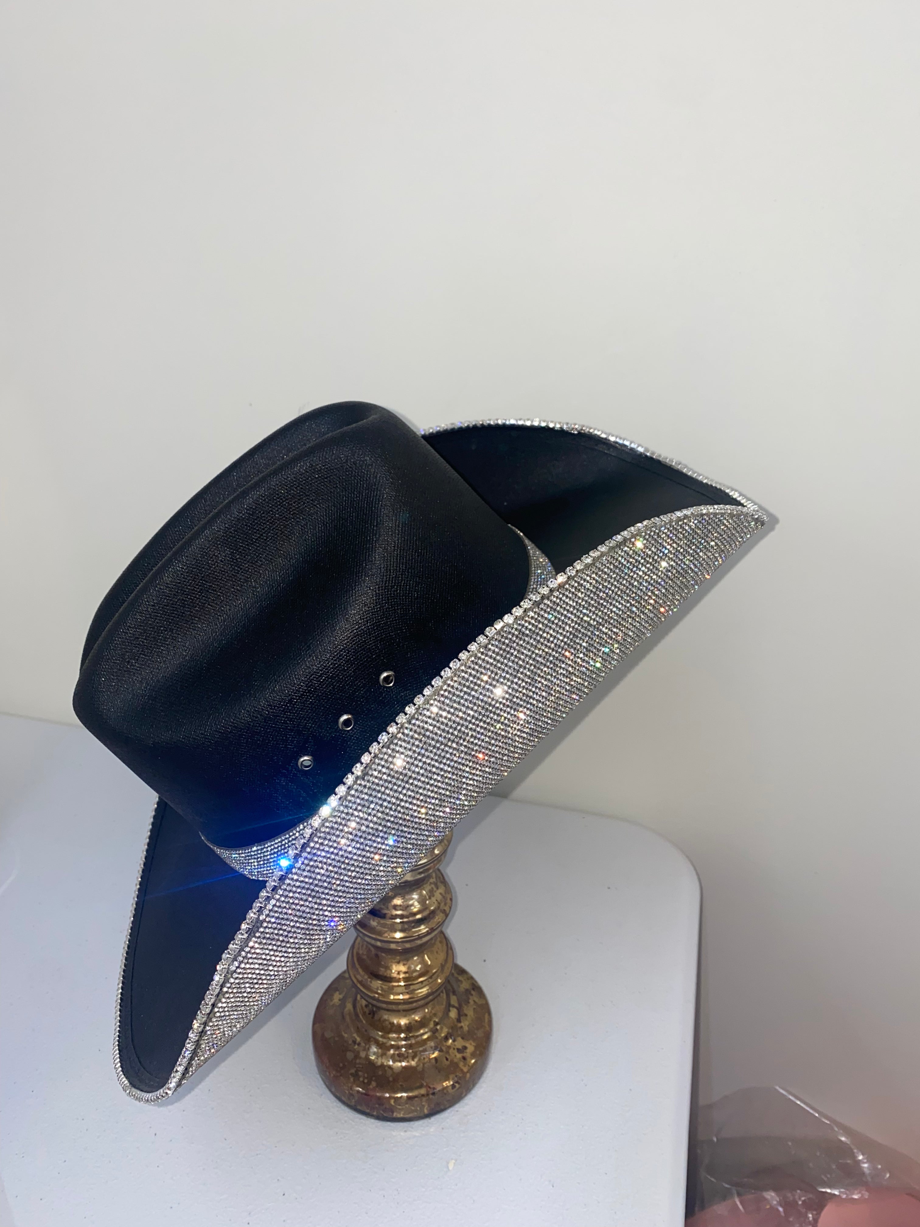 Decorative hat stand with blue and silver glittery top and gold base on a white surface.
