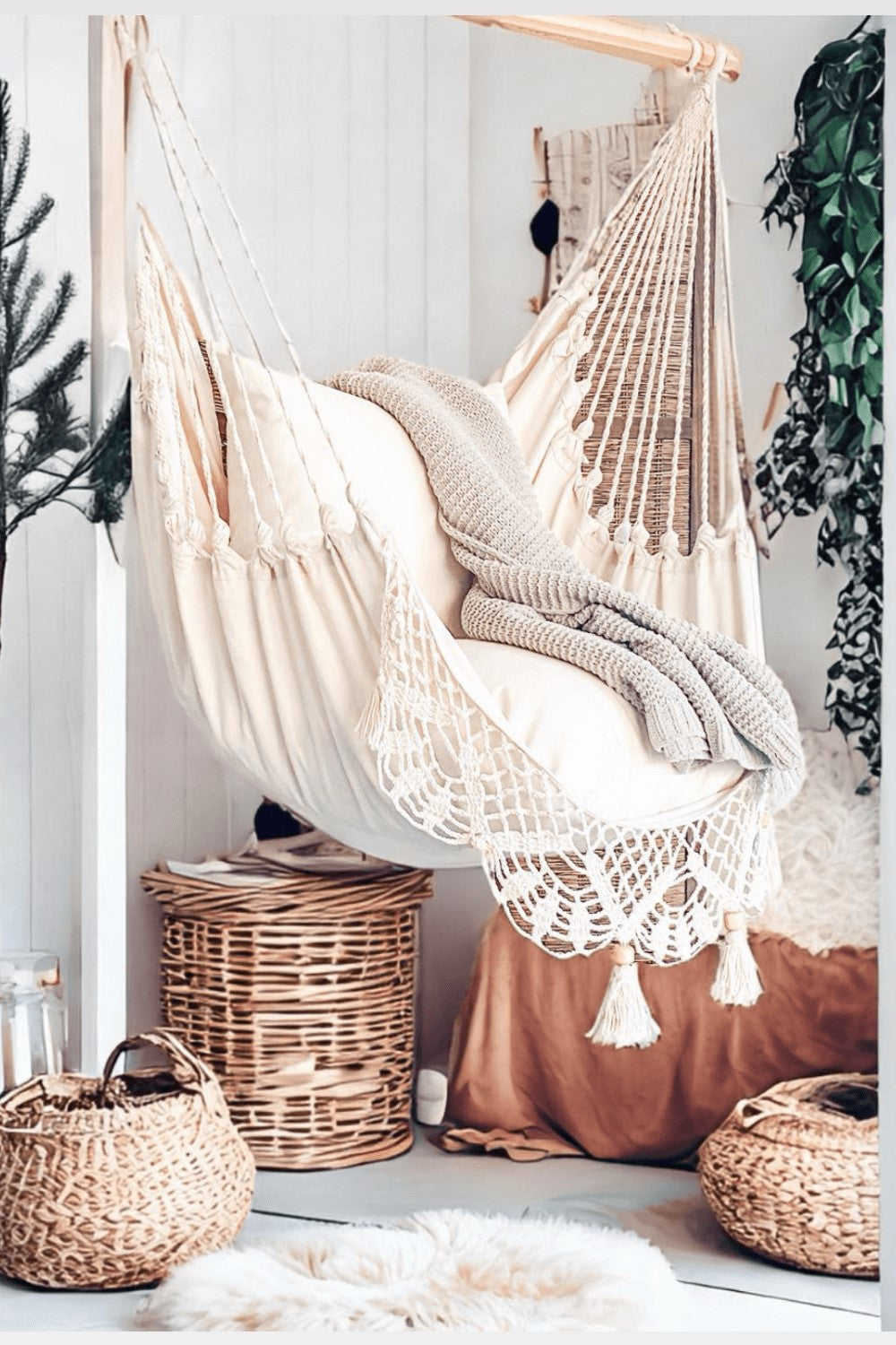 Beige hammock with a blanket in a room with wicker baskets and plants.