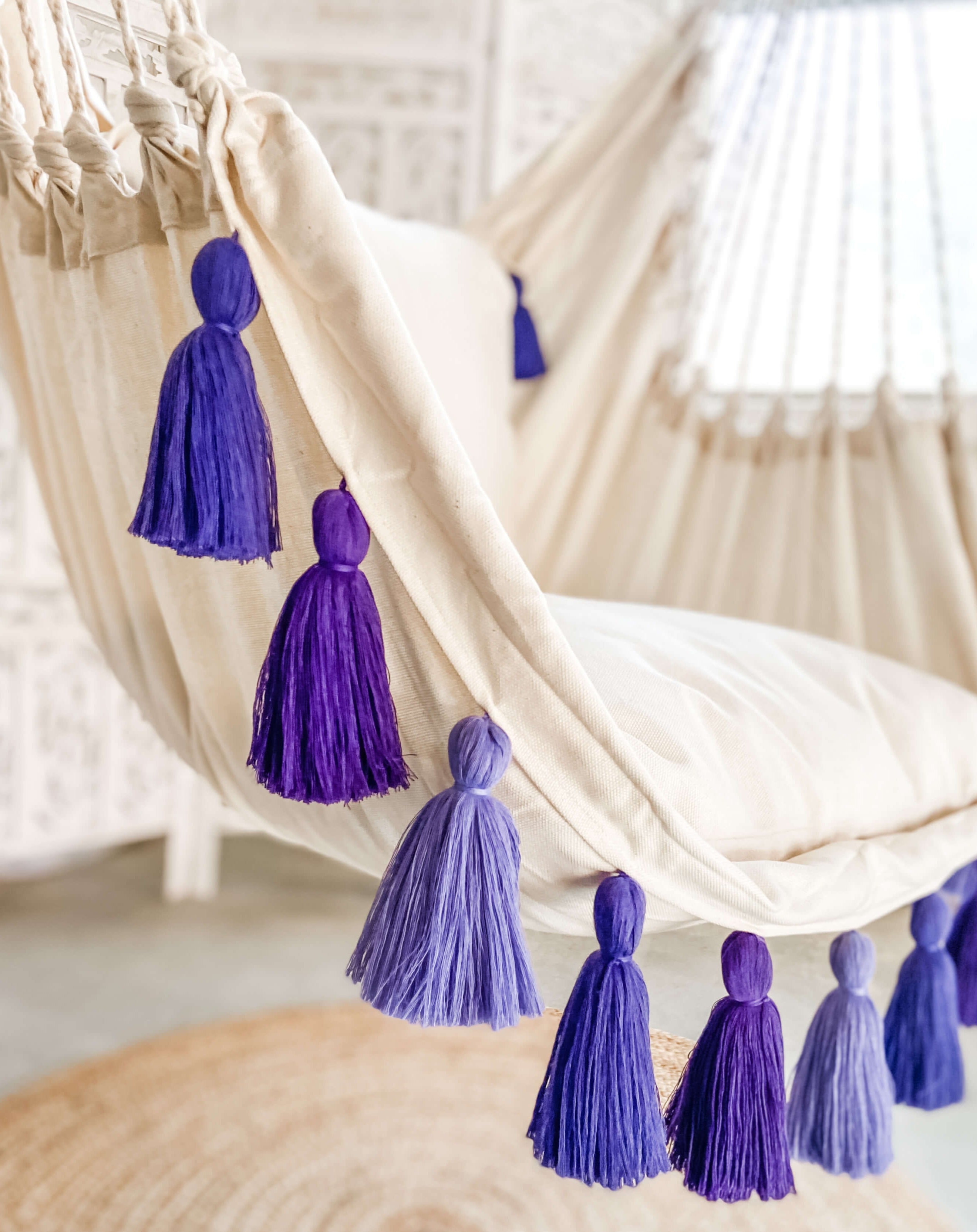 Purple tassels hanging from a beige hammock with a blurred background